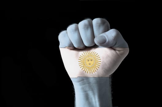 Low key picture of a fist painted in colors of argentina flag