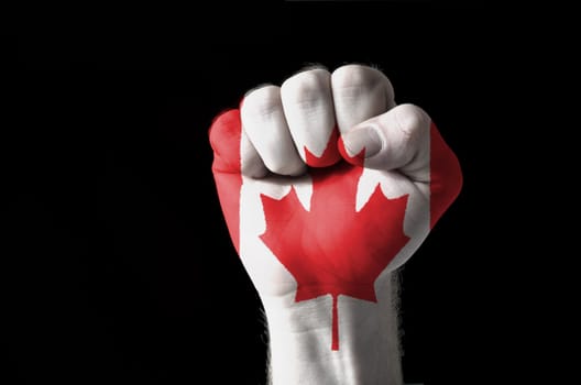 Low key picture of a fist painted in colors of canada flag