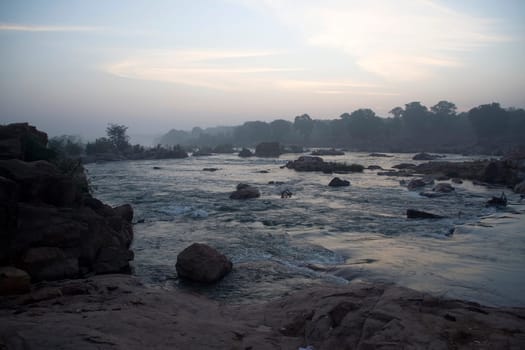 Fierce flow of river water gushing through between rocks