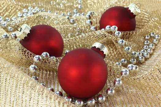 three Christmas tree baubles on golden decorative fabric