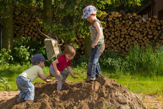 Children playing in the pile of sand,taped wood in the background
