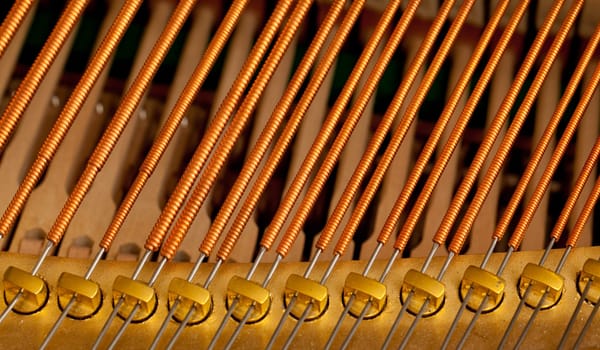 Close up image of interior of grand piano showing strings and structure