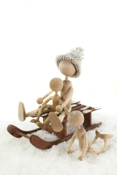 Wooden dolls sledding in the snow