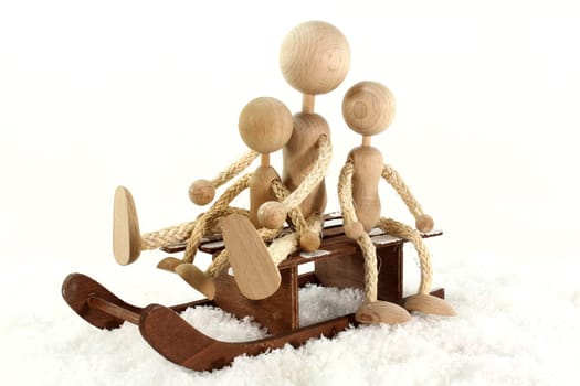 Wooden dolls sledding in the snow