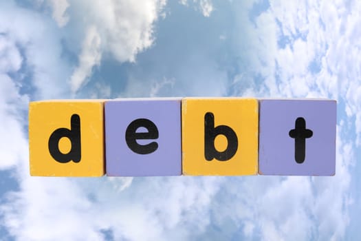 assorted childrens toy letter building blocks against a cloud background that spell debt with clipping path