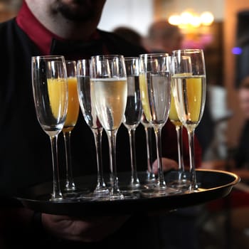 Waiter serving tray with sparkling wine and Champagne - square