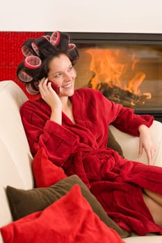 Home beauty woman with curlers calling phone fireplace red bathrobe