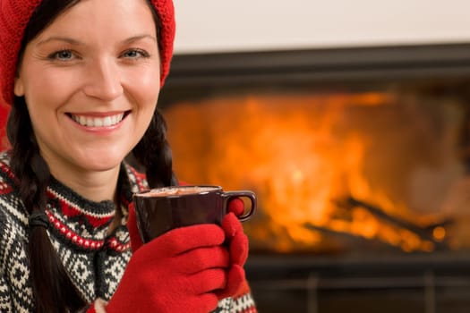 Winter Christmas woman with hat and gloves drink by fireplace