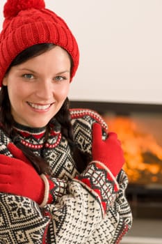 Winter christmas happy woman with hat and gloves by fireplace