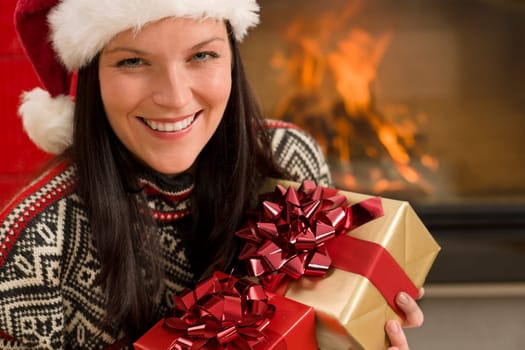 Xmas present happy woman by home fireplace wear Santa hat