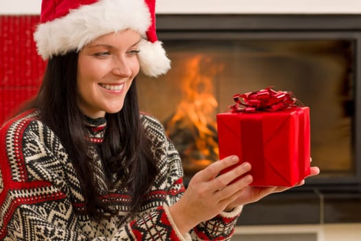 Xmas present happy woman by home fireplace wear Santa hat