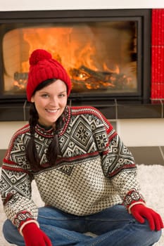 Happy woman warming up by home fireplace wear Christmas sweater
