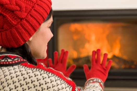 Happy woman warming up by home fireplace wear Christmas sweater