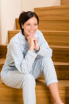 Happy morning young woman in pajamas sitting on the stairs