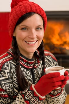 Winter christmas woman with hat and gloves drink by fireplace