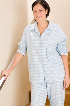 Happy morning young woman in pajamas standing on the stairs