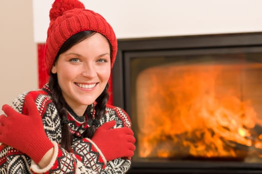 Happy woman warming up by home fireplace wear christmas sweater