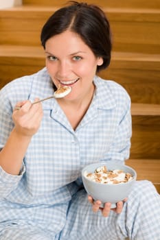 Home breakfast happy woman in pajamas eating cereals on stairs