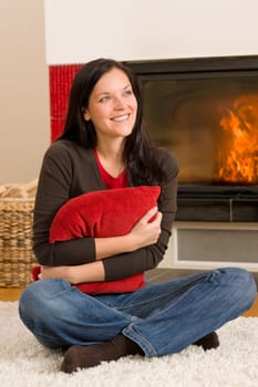 Beautiful happy young woman sitting front of home fireplace