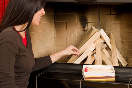 Young woman lighting up wood logs in fireplace home living