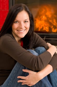 Beautiful happy young woman sitting front of home fireplace