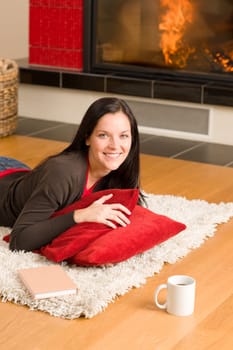 Happy young woman lying on rug by fireplace home living
