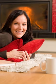 Happy young woman lying on rug by fireplace home living