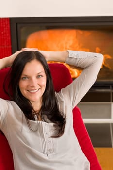 Young woman relax on red armchair by home fireplace
