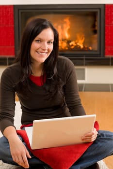 Home living happy young woman by fireplace working on laptop