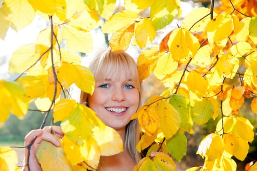 Teenager looking through autumn leaves