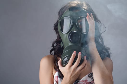 Female wearing a gas mask for protection against the cigarette smoke