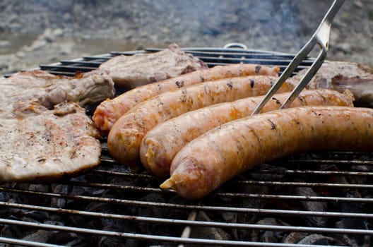 Sausages and pork cooking on the grill