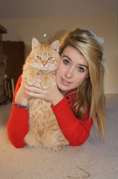 Girl laying on her bedroom floor cuddling her pet cat