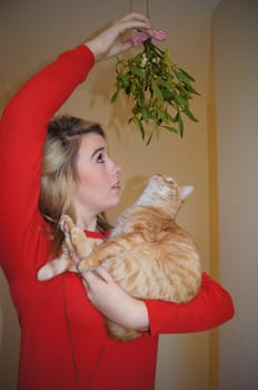 Girl and her pet cat under the mistletoe