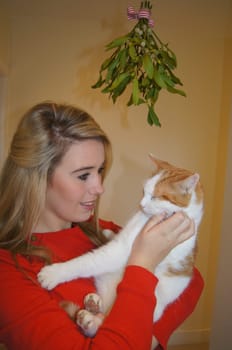 Girl and her pet cat under the mistletoe