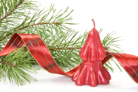 red christmas candle and pine branch over a white background