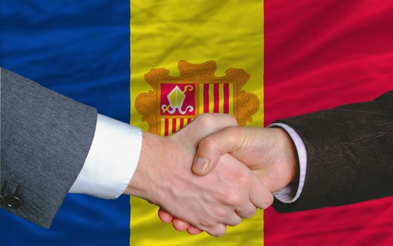 two businessmen shaking hands after good business investment  agreement in andora, in front of flag