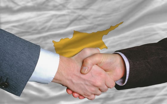 two businessmen shaking hands after good business investment  agreement in cyprus, in front of flag