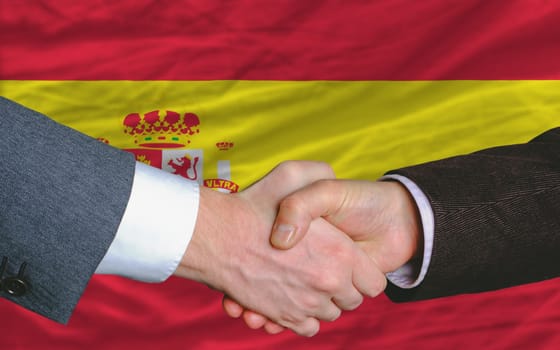 two businessmen shaking hands after good business investment  agreement in spain, in front of flag