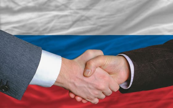 two businessmen shaking hands after good business investment  agreement in russia, in front of flag