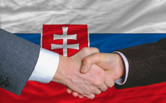 two businessmen shaking hands after good business investment  agreement in slovakia, in front of flag