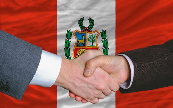 two businessmen shaking hands after good business investment  agreement in peru, in front of flag