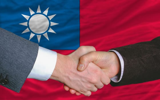 two businessmen shaking hands after good business investment  agreement in taiwan, in front of flag