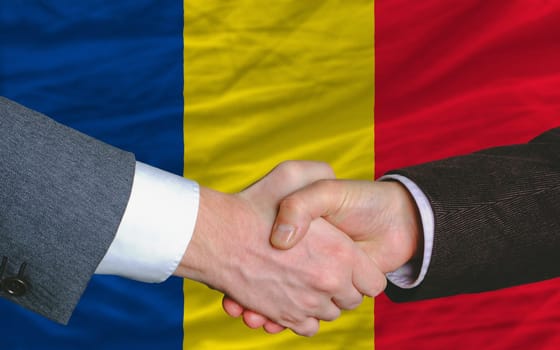 two businessmen shaking hands after good business investment  agreement in romania, in front of flag