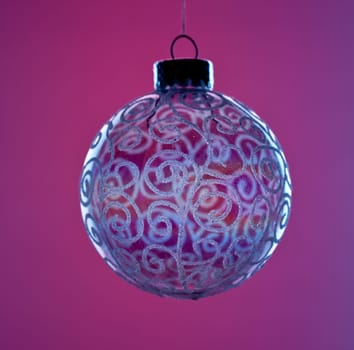 Single round globe glass xmas decoration against red background with blue edges