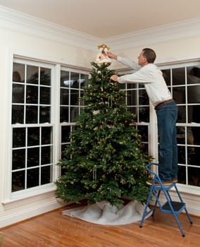 Senior man decorating a Christmas tree in family home