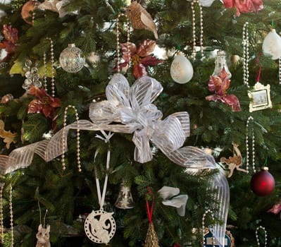 Christmas tree decorated with silver and white ribbons and ornaments in family home