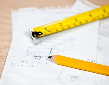 Tape measure and pencil laying on plans for a woodworking project