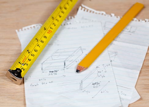 Tape measure and pencil laying on plans for a woodworking project