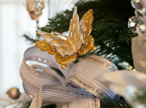 Christmas tree decorated with silver and white ribbons and butterfly ornaments in family home